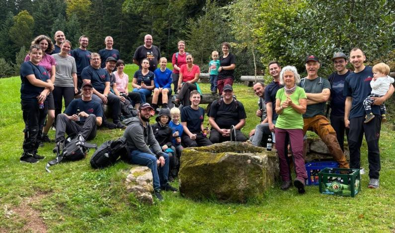 Feuerwehrangehörige posieren für ein Gruppenfoto an einem kleinen Brunnen